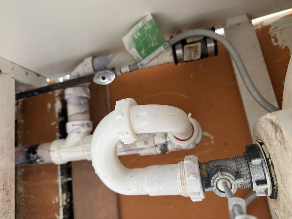 New white PVC P-trap and supply lines fitted neatly under a bathroom sink