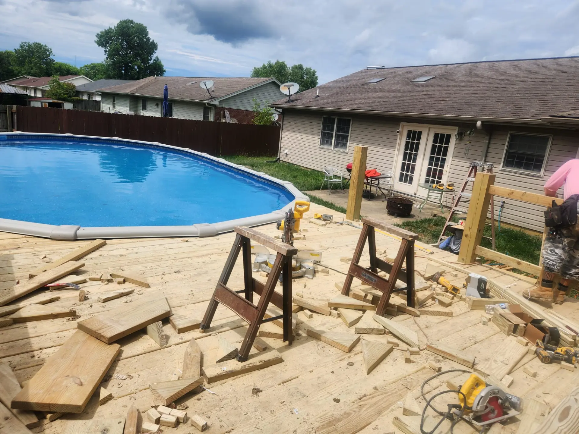 Pool surround deck mid-build with fresh timber boards, saw horses and railing posts going in