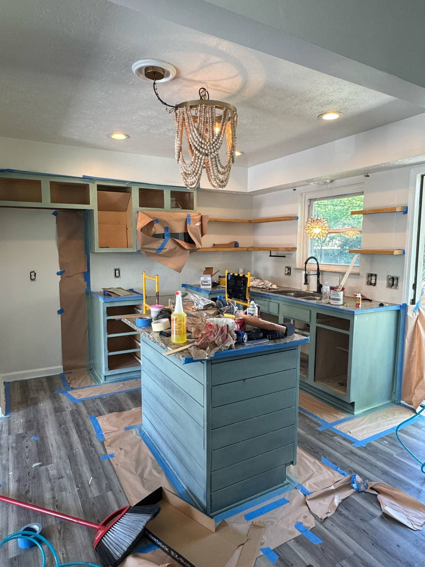 Kitchen fully masked with painter's tape, paper floor protection and covered worktops mid-spray