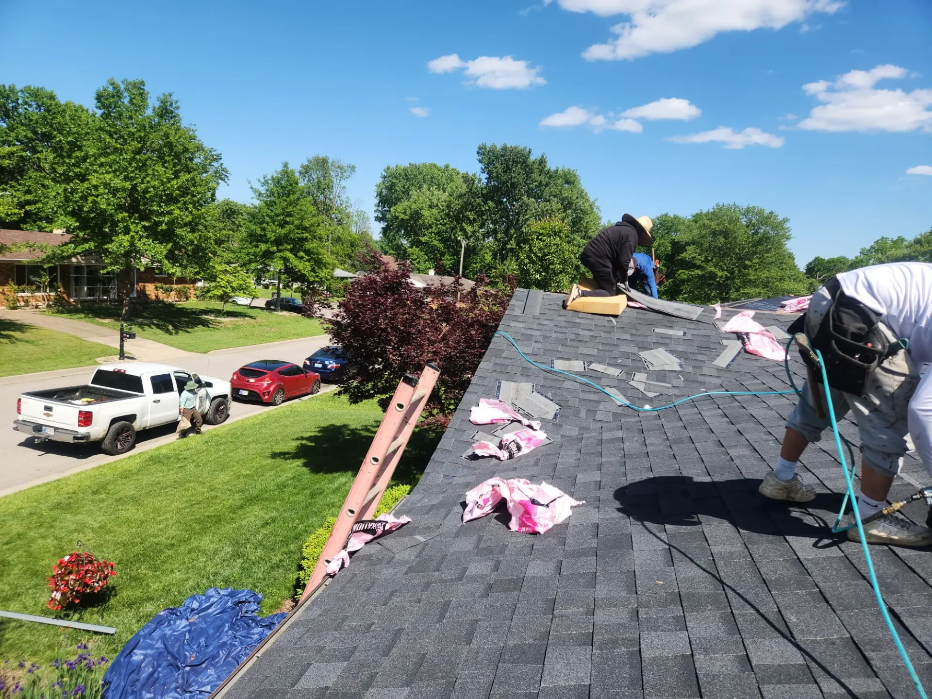 Roofers replacing asphalt shingles on a residential roof on a clear summer day