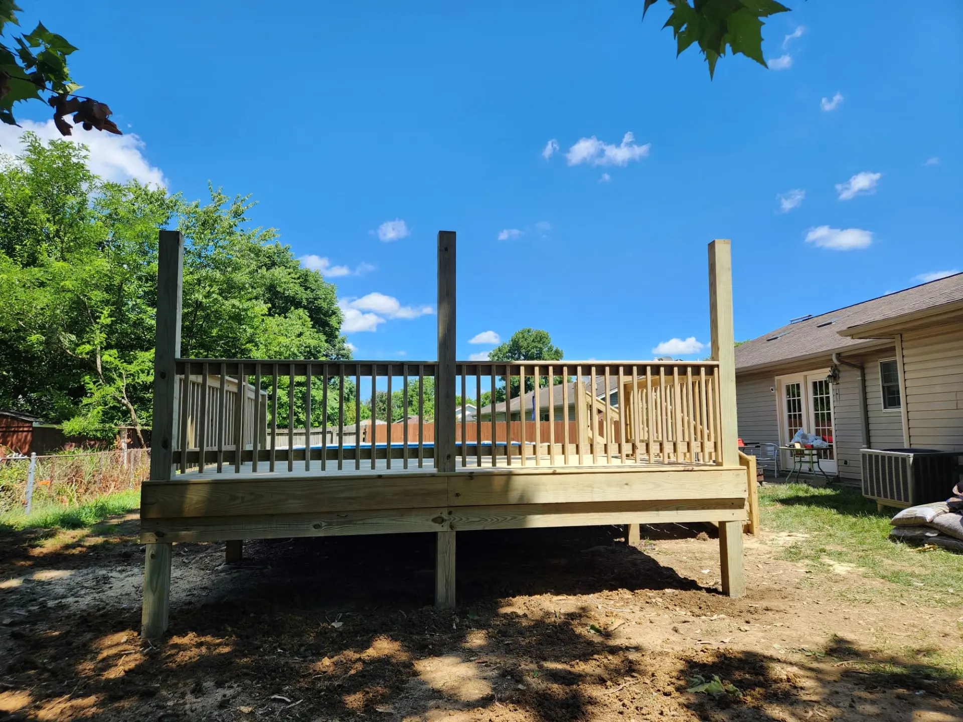 Finished raised timber pool deck with balustrade railing overlooking an above-ground pool
