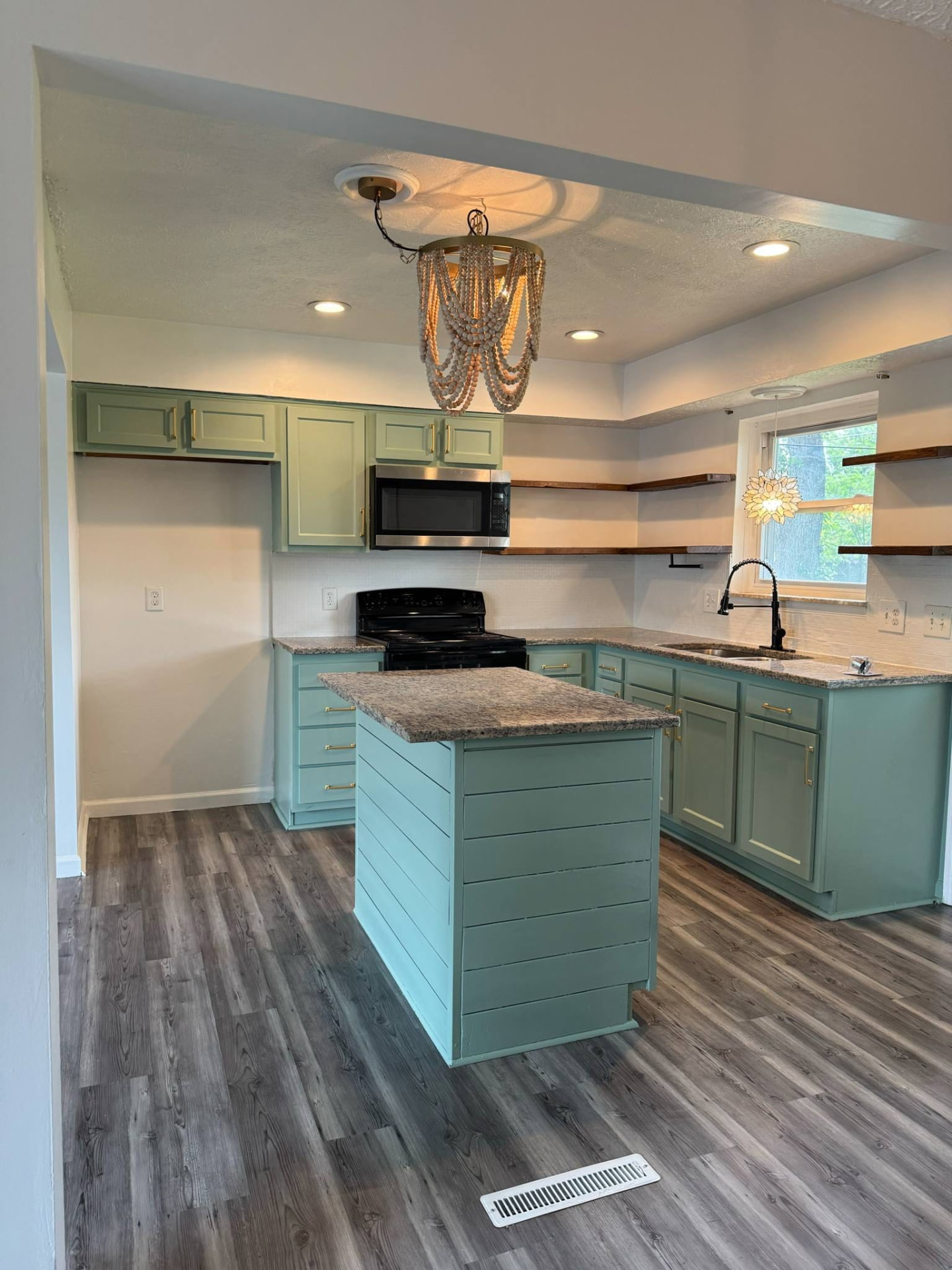 Renovated kitchen with sage green shaker cabinets, shiplap island, granite worktops and reclaimed timber open shelving