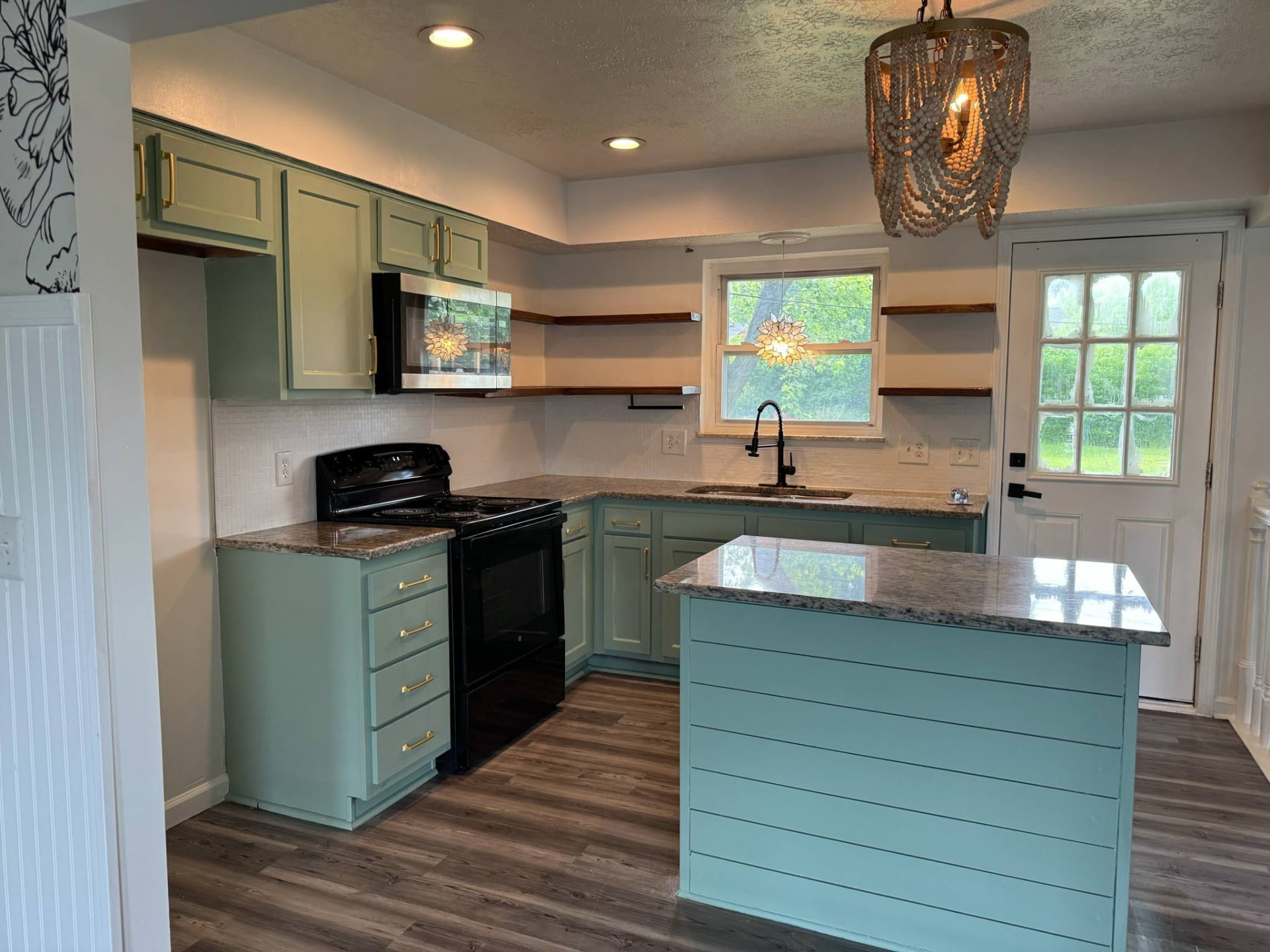Finished kitchen renovation with repainted sage green cabinets, brass hardware and beaded chandelier